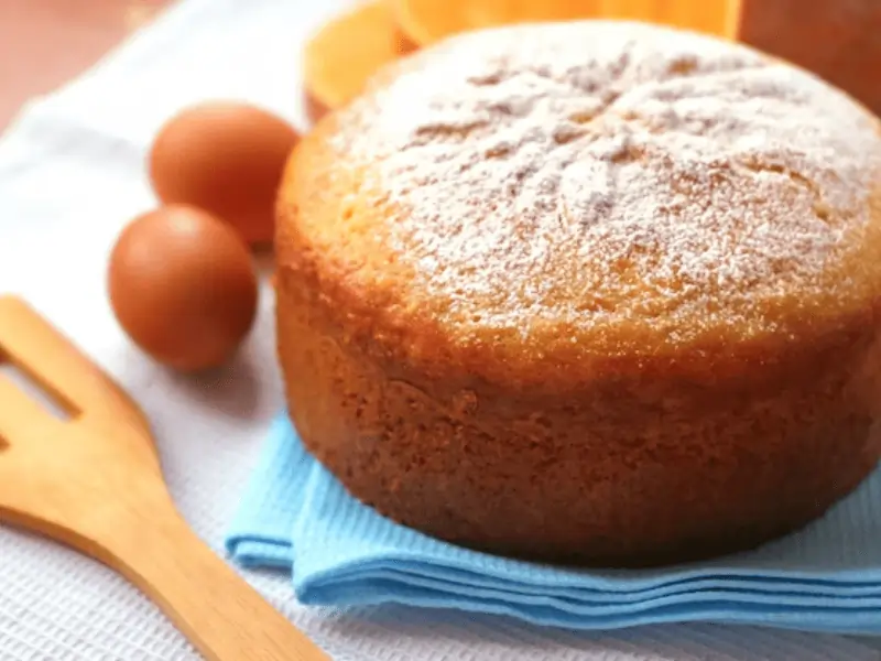 Bizcocho de calabaza Thermomix decorado con azúcar glass, servido sobre un plato de cerámica con fondo otoñal