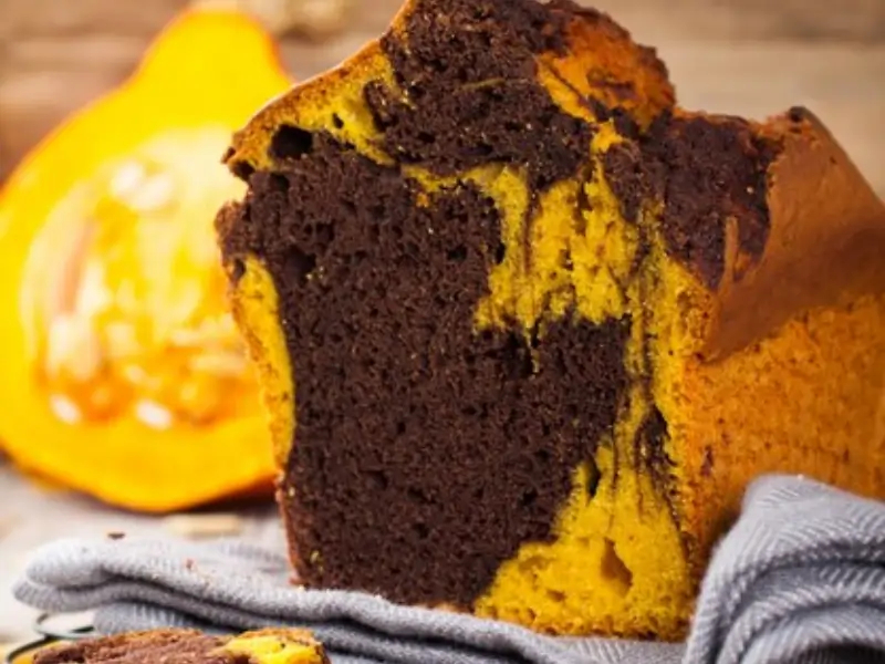 Bizcocho de calabaza y chocolate recién horneado, esponjoso y decorado con ganache de chocolate y almendras.