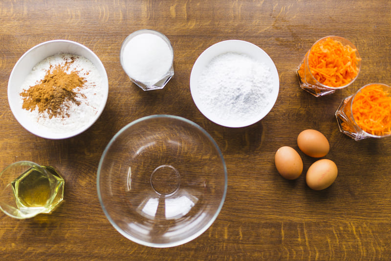 Ingredientes básicos para un bizcocho: harina, huevos, azúcar, mantequilla y leche sobre una mesa de cocina.